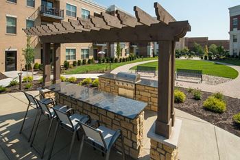 A patio with a stone bench and a wooden pergola.